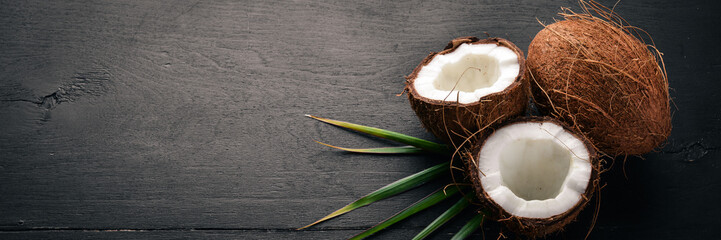 Coconut on a wooden background. Tropical fruits and nuts. Top view. Free space for text. - obrazy, fototapety, plakaty