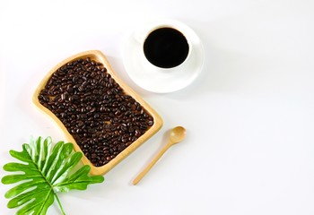 Flat lay photo with Coffee beans in wooden plate, Coffee Cup, Spoon and tropical Leaf isolated on white background with copy space
