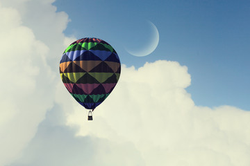 Aerostat floating in day sky. Mixed media