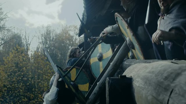 Large-Scale Medieval Battle Reenactment. Violent Tribe of Warriors Attack Wooden Fortress Wall, They Climb Ladders, Guards Try to Defend Fortification. Shot on RED EPIC-W 8K Helium Cinema Camera.