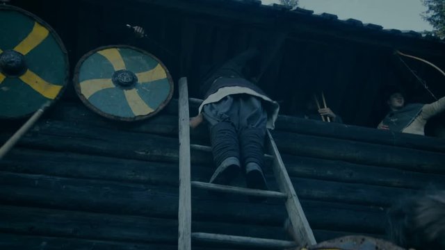 Large-Scale Medieval Battle Reenactment. Violent Tribe of Warriors Attack Wooden Fortress Wall, They Climb Ladders, Guards Try to Defend Fortification. Shot on RED EPIC-W 8K Helium Cinema Camera.