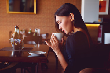 Young brunette with a coffee cup in a restaurant