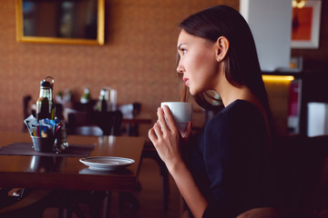 Young brunette with a coffee cup in a restaurant