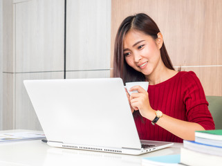Young beautiful Asian woman working in office, using computer laptop about business work and online shopping, smile and happy with copy space,
