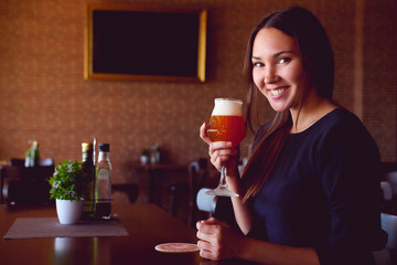 Young brunette drinking a beer in a restaurant