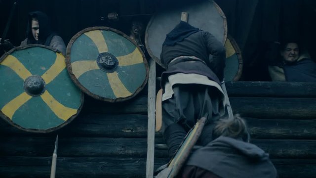 Large-Scale Medieval Battle Reenactment. Violent Tribe of Warriors Attack Wooden Fortress Wall, They Climb Ladders, Guards Try to Defend Fortification. Shot on RED EPIC-W 8K Helium Cinema Camera.