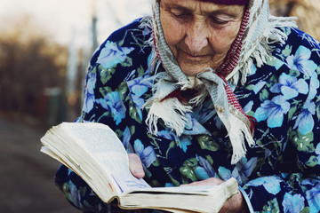 Fototapeta premium The old grandmother is reading a book-Bible