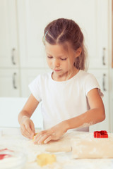 Cute little kid girl 6 years old cook apple pie for dinner. Child prepares the dough at home in the kitchen. Healthy food at home.