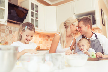 Parents and their two beautiful and cute children girls eating breakfast ot lunch at kitchen table at home