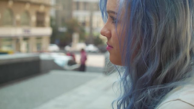 Beautiful blue hair young girl sitting at street stairs and thinking