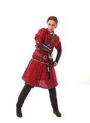 portrait of a red haired girl wearing medieval warrior outfit, studio background.