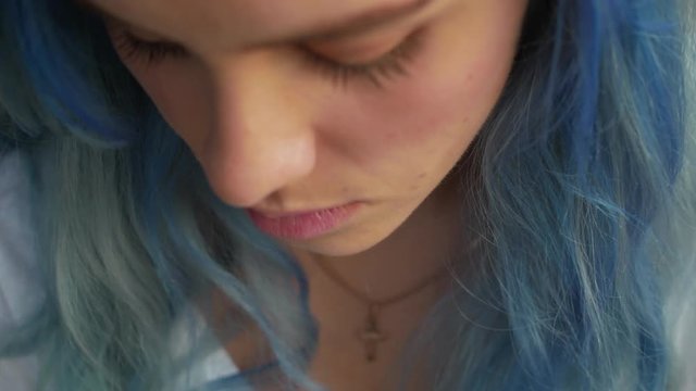 Young pretty blue hair sorrow girl with Christian cross at the street portrait