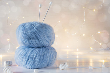 Two blue fluffy ball yarn and knitting needles. Christmas background.