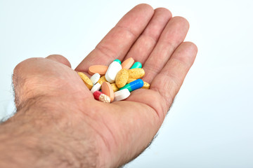 The hand of a man with different types of medication, Medicine pills or capsules in hand, palm. Colorful pills and medicines in the hand