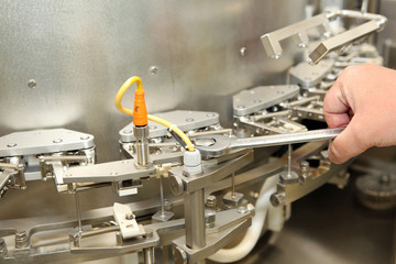 Repair and adjustment of medical equipment. Validation of the machine for the production of pharmaceutics. Man repairing a machine for the production of medicines. Repairs to the machine hands of men.