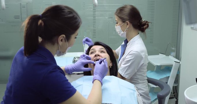Dentist and nurse make dental cleaning for a patient