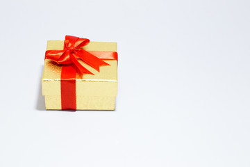 Gloden gift box with red bow on white background