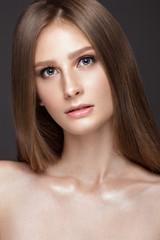 Fototapeta premium Beautiful young girl with a light natural make-up and perfect skin. Beauty face. Picture taken in the studio on a grey background.