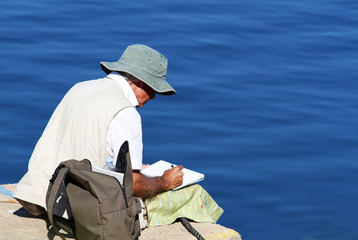 Man sitting on pier drawing
