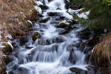 Fototapeta na wymiar Fast flowing creek cascading downstream (long exposure)