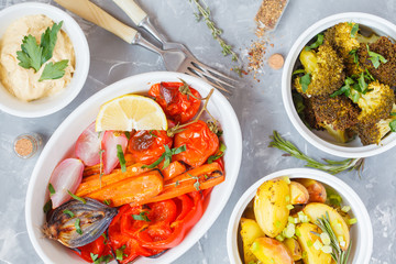 Mix of baked vegetables in white ceramic form with hummus, top view