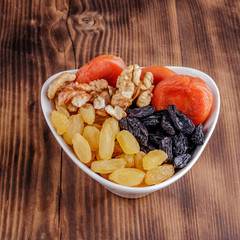 Mix of dried fruits and nuts on a dark wood background