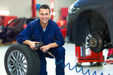 Car mechanic in workshop changing tires

