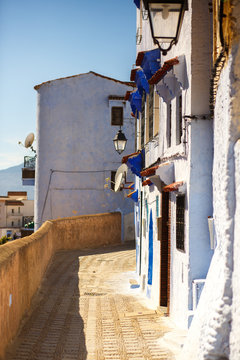 Sun shines over an old blue street of Morocco