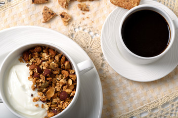 Obraz na płótnie Canvas Healthy breakfast: Greek yogurt with homemade granola in a white bowl, a cup of coffee and cereal cookies
