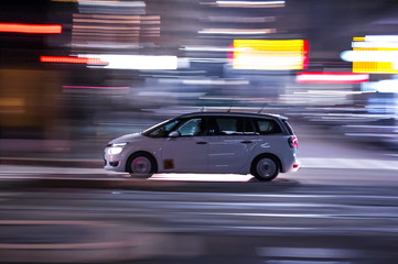 Automobile che sfreccia veloce di notte per le vie con luci colorate di una  grande città 