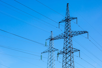 High-voltage power lines against the blue sky. Electricity distribution station.