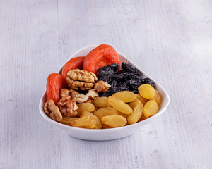 Mix of dried fruits and nuts on a white wooden background.