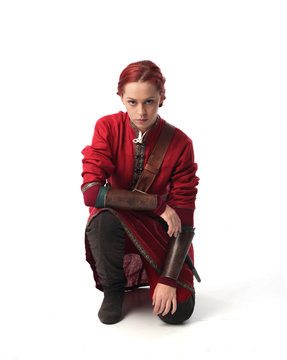 portrait of red haired girl wearing red medieval out fit, studio background.