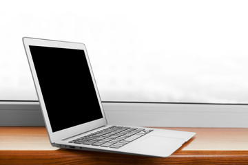 laptop with blank screen on wood table with office window view backgrounds