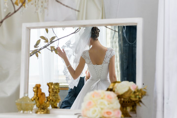 Wedding concept - the bride looks in the mirror