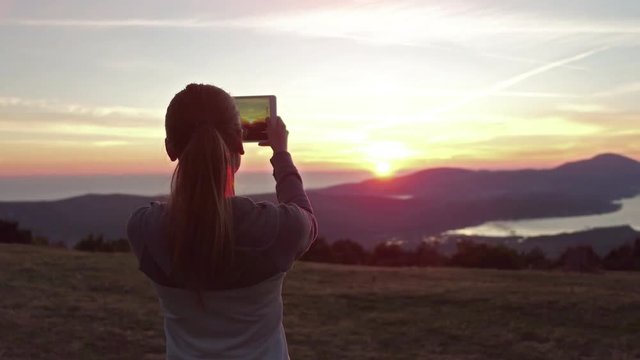woman hiker use digital tablet taking photo at mountain peak cliff