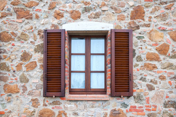 Old wooden windows frame on stone wall in Italy.
