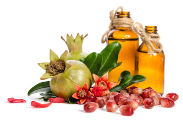  two green pomegranates, bottle with oil and leaves with petals on white background
