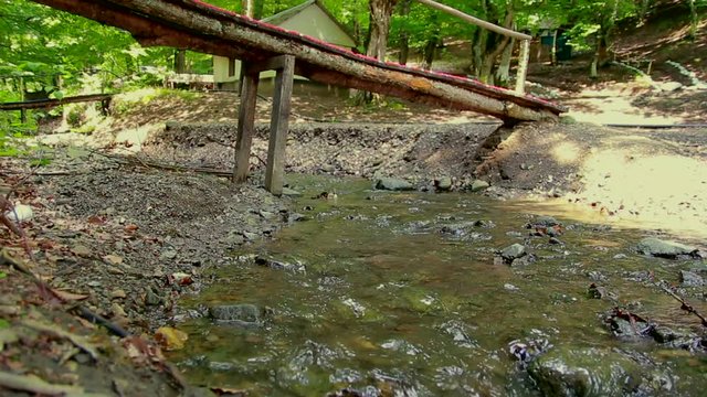 Old small wooden bridge on forest river.
