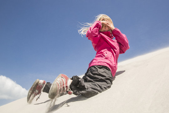 A girl in a sandstorm on the dunes of Wharariki Beach, Farewell Spit, South Island, New Zealand