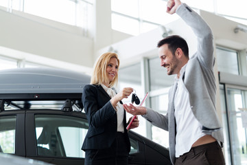 Professional salesperson selling cars at dealership to buyer