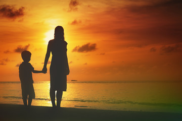 mother and son walking on sunset beach