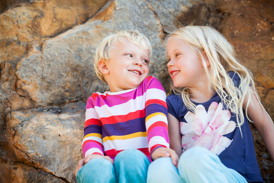 Boy and girl sitting on a rock and laughing, Port de Soller, Majorca, Balearic Islands, Spain, Europe