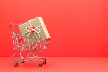 brown gift box in shopping cart on red paper background
