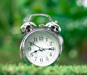 Retro alarm clock on green grass. time concept