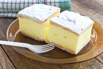 Cream pie with layers of puff pastry in plate on wooden table