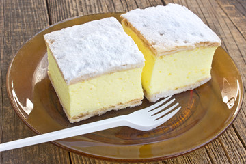 Cream pie with layers of puff pastry in plate on wooden table