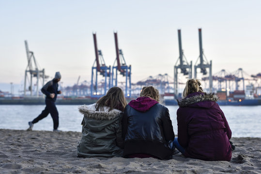 3 girls viewing the port at the Elbe River beach, Oevelgoenne, Hamburg, Germany, Europe