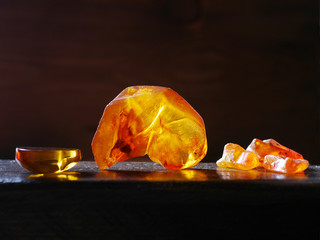 Bright beautiful untreated amber on a wooden background, backlit by backlight. Gems.