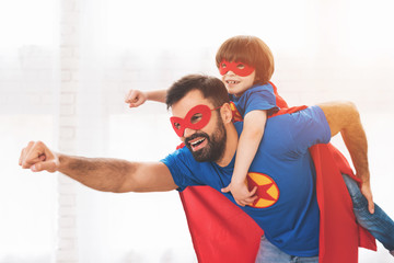 Father and son in the red and blue suits of superheroes. On their faces are masks and they are in...
